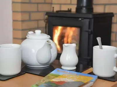 a table with vases and a book and a fireplace at Criffel View in Dumfries