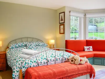 a bedroom with a bed and a red couch at The Smithy in New Galloway