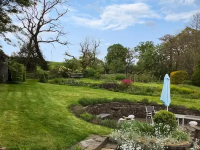 a garden with a pond and an umbrella at The Smithy in New Galloway