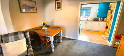 a dining room with a table and a kitchen at Tom's Place in Kirkcudbright