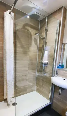 a shower with a glass door next to a sink at Tom's Place in Kirkcudbright