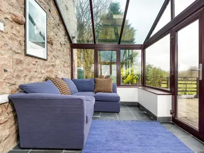 a conservatory with a blue couch in a room with windows at 3 Bed in Boot SZ502 in Eskdale