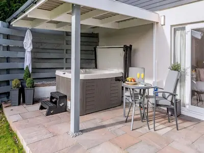 a patio with a hot tub and a table and chairs at 1 Bed in Sandyhills 85904 in Fairgirth