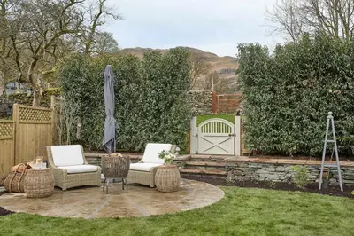 a patio with two chairs and an umbrella in a yard at The Little Cottage in Chapel Stile