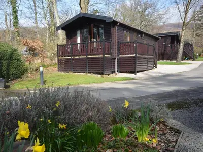a log cabin with a porch and flowers in front at 1 Bed in Keswick oc-82550 in Keswick