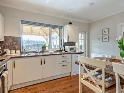 a kitchen with white cabinets and a sink and a window at 3 Bed in Cockermouth 82438 in Dearham