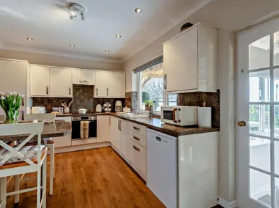 a kitchen with white cabinets and a large window at 3 Bed in Cockermouth 82438 in Dearham