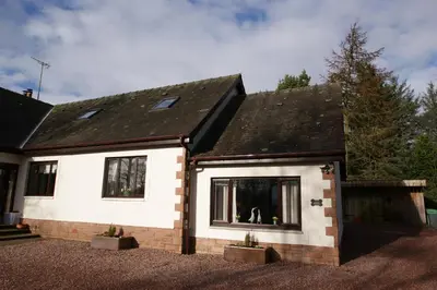 a white house with a dog in a window at Hollys Hideaway in Castle Douglas