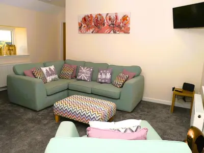 a living room with a green couch with pillows at Craigielea Cottage in Newton Stewart