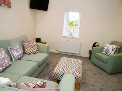 a living room with a green couch and two chairs at Craigielea Cottage in Newton Stewart