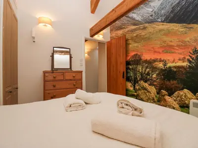 a bedroom with a bed with a painting on the wall at Taylor's Cottage in Keswick