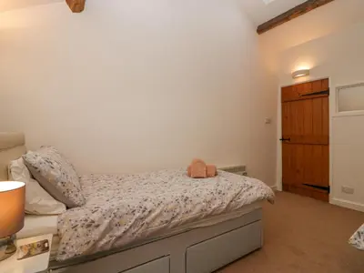 a bedroom with a bed with a teddy bear on it at Taylor's Cottage in Keswick