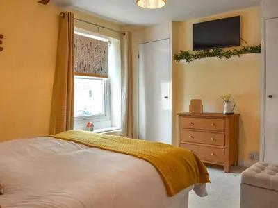 a bedroom with a bed and a window and a dresser at Daffodil Cottage in Cockermouth