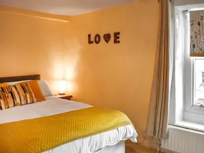 a bedroom with a bed with a love sign on the wall at Daffodil Cottage in Cockermouth