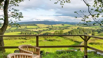 two chairs sitting on a balcony looking out over a valley at Crocus Penruddock, dog & eco friendly lodge with hot tub in Penruddock