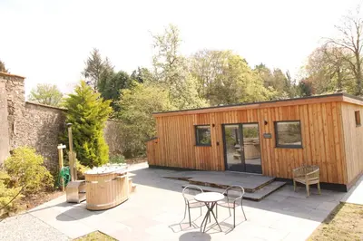 a small cabin with a table and chairs on a patio at Shepherds Retreat Hutton John in a walled garden in a rural setting only 10 minutes for Lake Ullswater in Penruddock