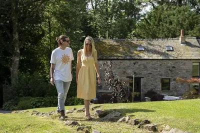two women walking down a path in front of a house at Shepherds Retreat Hutton John in a walled garden in a rural setting only 10 minutes for Lake Ullswater in Penruddock