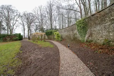 a path next to a stone wall next to a field at Shepherds Retreat Hutton John in a walled garden in a rural setting only 10 minutes for Lake Ullswater in Penruddock