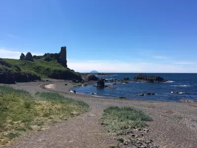 a rocky beach with a castle in the ocean at 1 Bed in Turnberry 78071 in Girvan