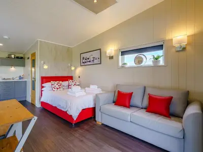 a bedroom with a couch and a bed with red pillows at 1 Bed in Turnberry 78071 in Girvan