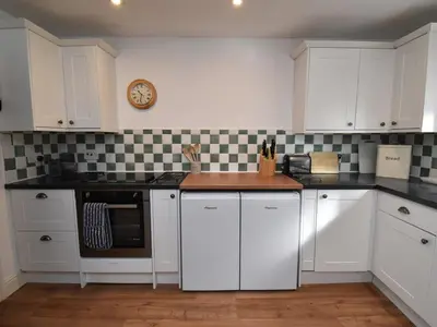 a kitchen with white cabinets and a clock on the wall at 2 Bed in Caldbeck SZ212 in Caldbeck