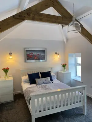 a bedroom with a white bed in a room at The Cottage, Bridge House in Laxey