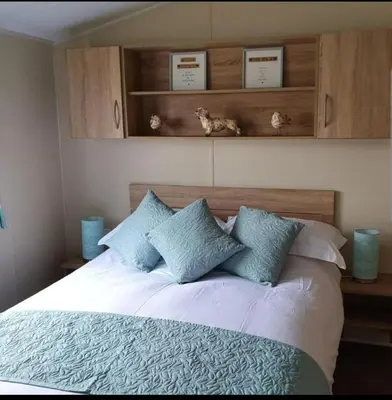 a bedroom with a white bed with blue pillows at Port Carlisle Caravan near Bowness on Solway in Carlisle