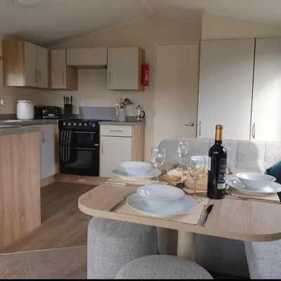 a kitchen with a table with plates and wine glasses at Port Carlisle Caravan near Bowness on Solway in Carlisle