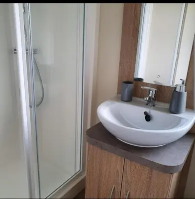 a bathroom with a white sink and a shower at Port Carlisle Caravan near Bowness on Solway in Carlisle