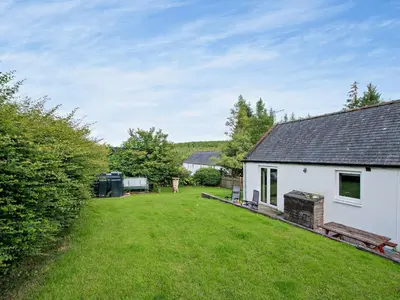 a white house with a large yard in front of it at 1 Bed in Balmaclellan CA371 in Castle Douglas