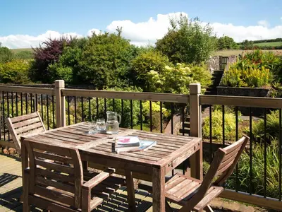 a wooden table and two chairs on a deck at 3 Bed in Egremont oc-sz230 in Hale