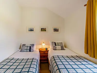two twin beds in a bedroom with a lamp on a night stand at 3 Bed in Keswick oc-sz148 in Grange