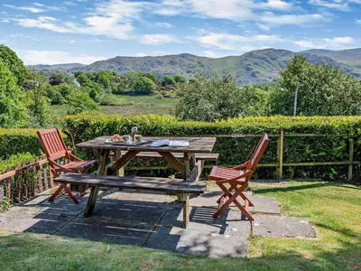 a picnic table and two chairs with a view of mountains at 3 Bed in Holmrook oc-sz414 in Santon Bridge