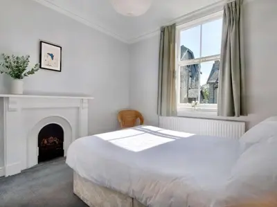 a white bedroom with a bed and a fireplace at 6 Bed in Keswick oc-sz389 in Keswick