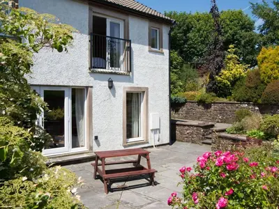 a bench in front of a house with flowers at 3 Bed in Egremont oc-sz058 in Hale