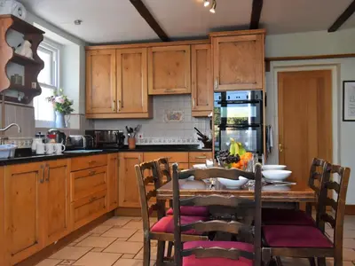 a kitchen with wooden cabinets and a table with chairs at 3 Bed in Threlkeld SZ421 in Threlkeld