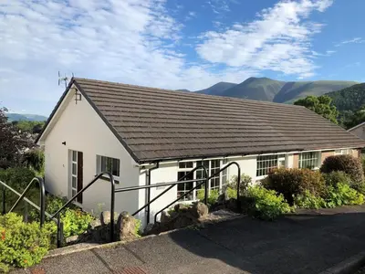 a white building with a roof with mountains in the background at 2 Bed in Keswick oc-sz116 in Keswick
