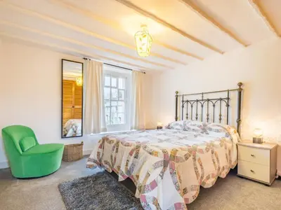a bedroom with a bed and a green chair at 2 Bed in Keswick oc-sz415 in Bassenthwaite