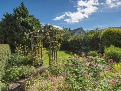 a garden with a wooden arbor in the middle of a yard at 2 Bed in Keswick oc-sz415 in Bassenthwaite