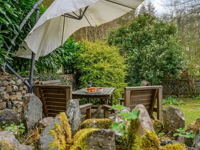 a table and chairs with an umbrella in a garden at 3 Bed in Keswick oc-sz065 in Applethwaite