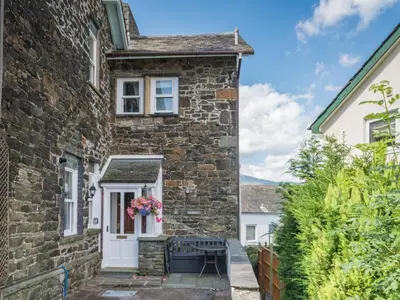 a stone house with a white door and flowers on it at 2 Bed in Keswick oc-sz490 in Keswick