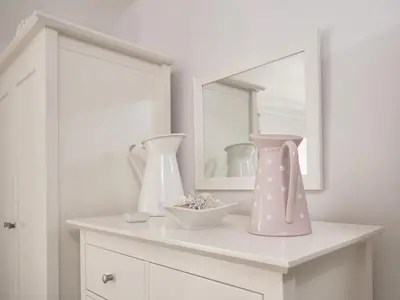 a white cabinet with a pink vase and a mirror at 4 Bed in Keswick oc-sz434 in Applethwaite