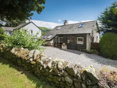 an old stone wall in front of a cottage at 3 Bed in Applethwaite SZ328 in Applethwaite