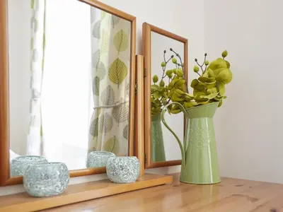 a green vase sitting on a table next to a mirror at 5 Bed in Keswick oc-sz291 in Keswick