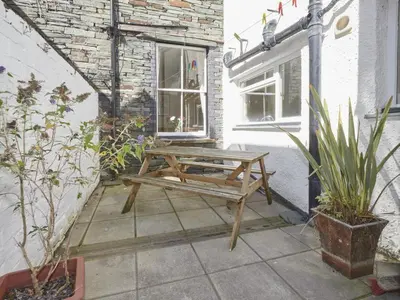 a wooden picnic table on a patio with plants at 5 Bed in Keswick oc-sz291 in Keswick