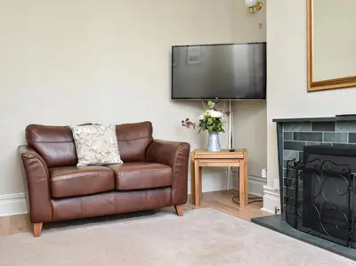 a brown leather chair in a living room with a fireplace at 5 Bed in Keswick oc-sz291 in Keswick