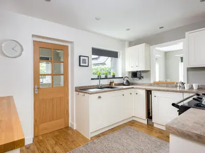 a kitchen with white cabinets and a wooden door at 4 Bed in Keswick oc-sz219 in Grange