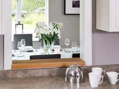 a kitchen mirror with a table with glasses and flowers at 4 Bed in Keswick oc-sz219 in Grange