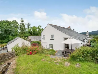 a white house with a table and an umbrella at 4 Bed in Routenbeck SZ405 in Bassenthwaite Lake