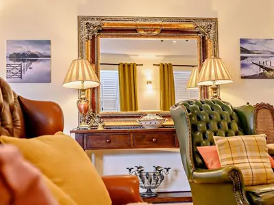 a living room with a mirror and a green chair at 4 Bed in Penrith oc-sz367 in Dockray